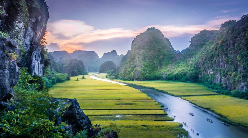 Rijstvelden en kalksteenbergen bij Tam Coc in Ninh Binh, met een rivier die door het dal slingert