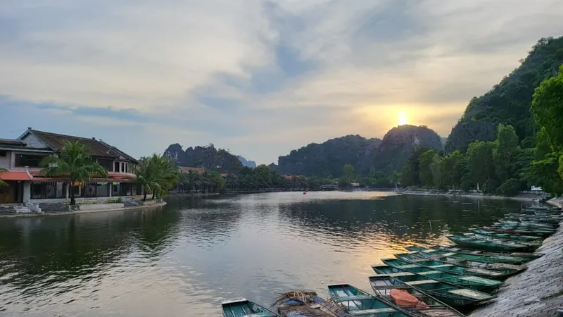 Zonsondergang boven de rivier en de bootjes in Tam Coc